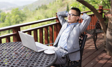 Businessman relaxing at table with laptop & coffee